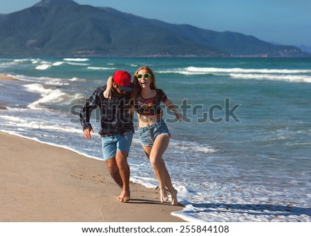couple in love walk on the sea playing happily at sunset