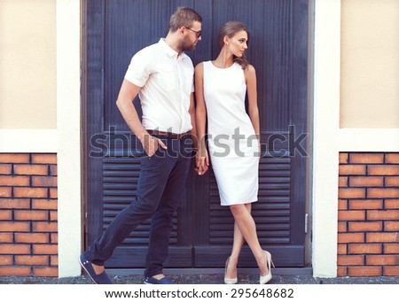 fashion couple standing in the European quarter, in a white dress, posing love at sunset.