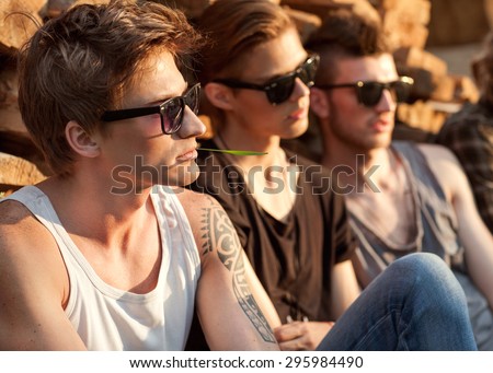 fashion guys friends sitting on the grass, wood backgrounds, sunset