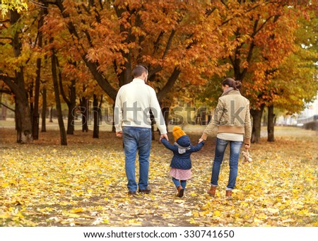 Family with a small daughter walk in autumn park