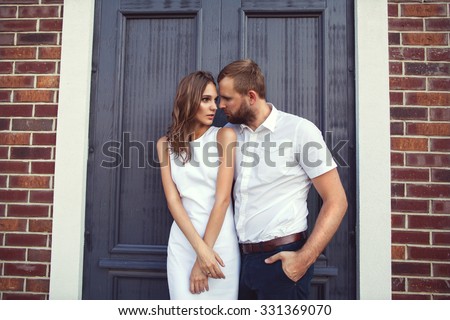 fashion couple standing in the European quarter, in a white dress, posing love at sunset. Quarrels.