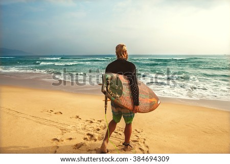 Surfer at the sea is standing with a surf board bright color.