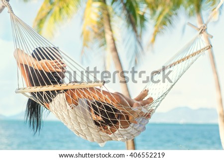 happy mother with her daughter lying in a hammock on the shore of a tropical beach. Mothers day.