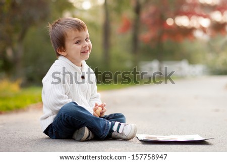 Boy, sitting on a path in a park
