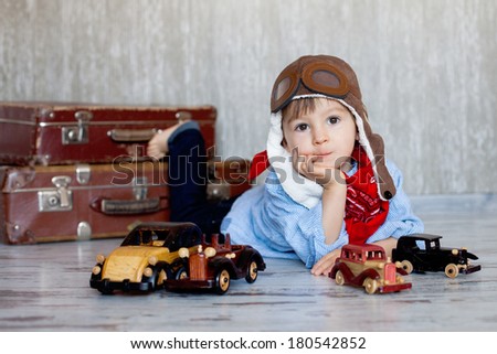 Little boy, playing with wooden cars, indoor, suitcases behind him