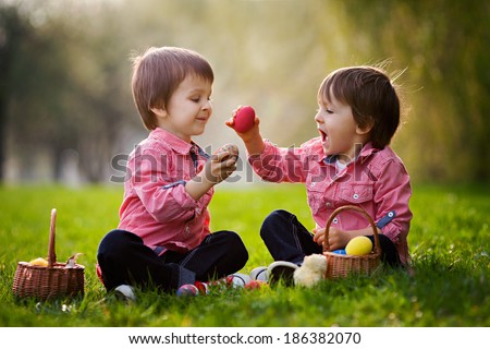 Two boys in the park, having fun with colored eggs for Easter