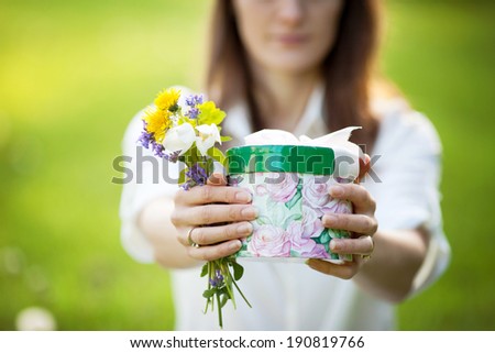 Young girl holding box with present and flowers for Mothers day
