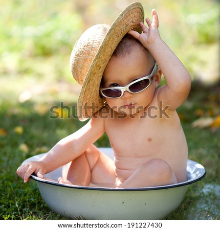 Sweet kid in a big wash basin with a straw hat