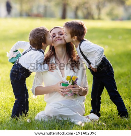 Beautiful kids and mom in spring park, flower and present. Mothers day celebration concept