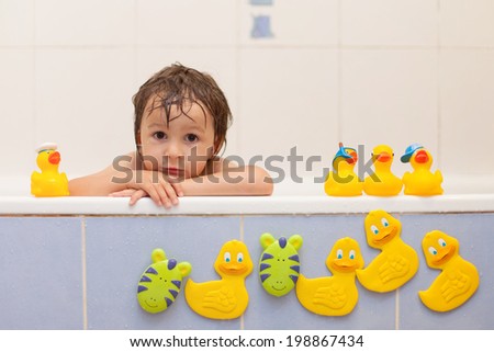Adorable little boys in bathtub with his rubber duckies