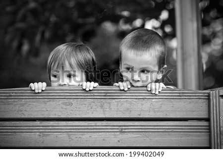 Two curious boys, looking over a wooden wall