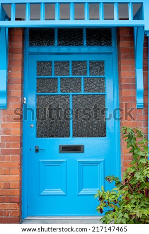 Brightly colored traditional English house door with a plant in front