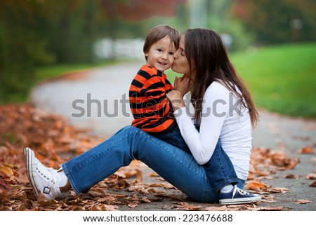 Kid playing isolated portrait. Young mother her boy outdoor in the park