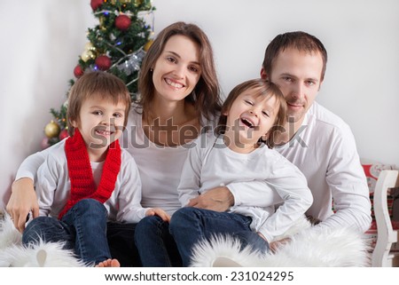 Portrait of friendly family of four, looking at camera on Christmas evening