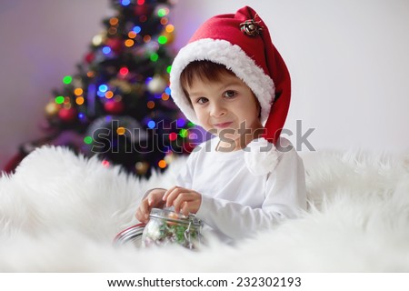 Cute adorable boy enjoying his candy at christmas time, holding jar with candies