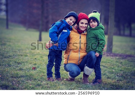 Adorable colorful portrait of a mother with her two boys, outdoor, vintage filter