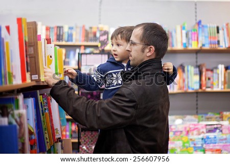Adorable little boy, sitting in a book store, looking at books