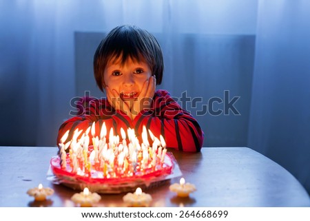 Adorable cute boy, blowing candles on a birthday cake at home