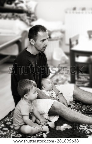 Father and his two sons, watching TV in the living room, black and white conversion