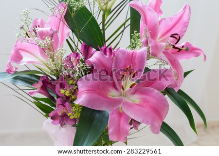 Pink lilies bouquet on a white background, green leaves