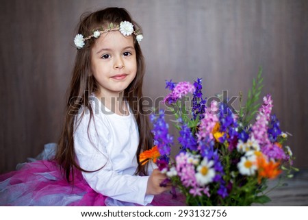 Close portrait of a little sweet smiling girl holding bouquet of flowers