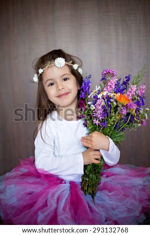 Close portrait of a little sweet smiling girl holding bouquet of flowers