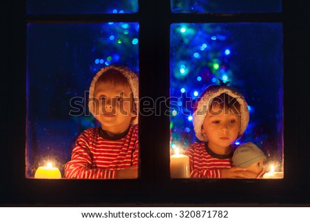 Two sweet boys, sitting on a window, looking outdoor, wintertime, waiting impatiently for Christmas to come