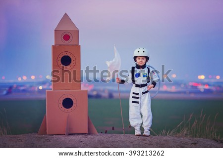 Adorable little boy, dressed as astronaut, playing in the park with rocket and flag, dreaming about becoming an astronaut
