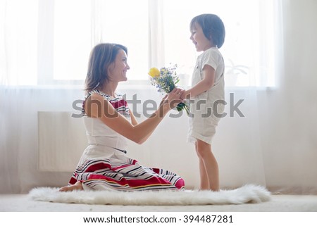 Mother and her child, embracing with tenderness and care, child  giving mother flowers. Mother day concept, happiness and love