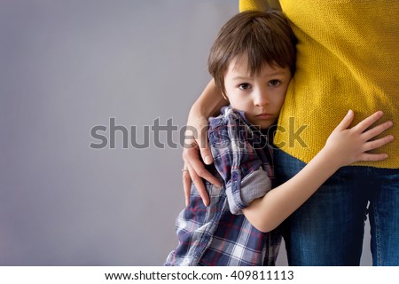 Sad little child, boy, hugging his mother at home, isolated image, copy space. Family concept