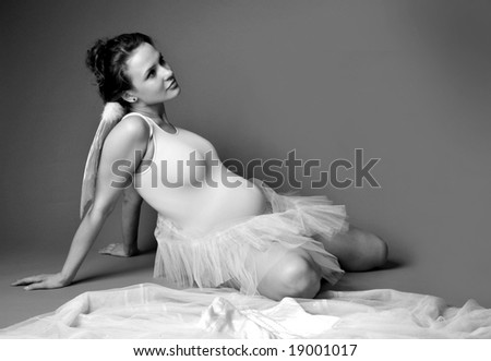 Pregnant woman on a grey background with angel wings