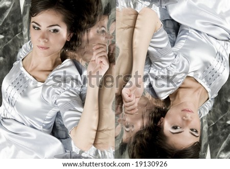 A beautiful young girl lies on a brilliant background in silver clothes