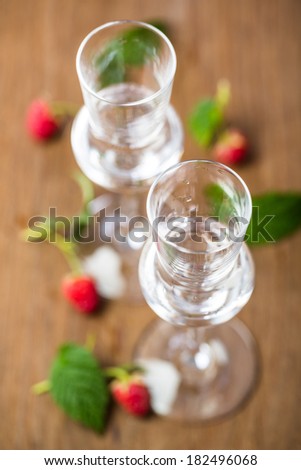 a birds eye view of two glasses of raspberry brand with raspberries on wooden board