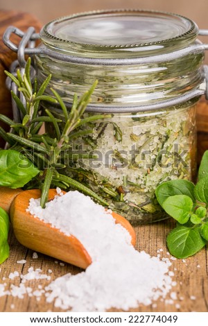 Extract of herb salt with ingredients on wooden board