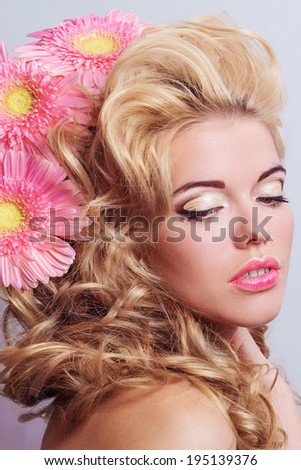 BEAUTY portrait of a girl with pink flowers in her hair. Portrait of blonde hair with volume. Professional make-up