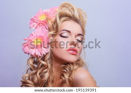 BEAUTY portrait of a girl with pink flowers in her hair. Portrait of blonde hair with volume. Professional make-up