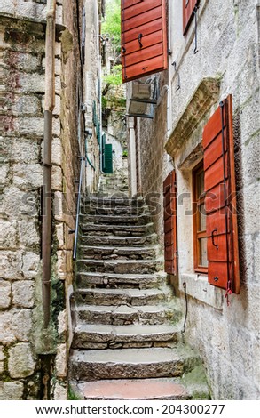 Old stone stairs through a narrow alley with red shutters in the old town of Kotor, one of the most famous places on Adriatic coast of Montenegro.