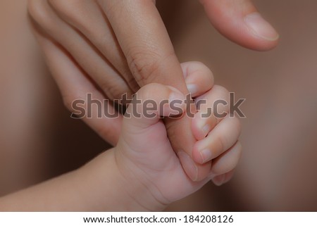 Love is not a dream concept of love. Hand in hand with love of mother and baby, closeup