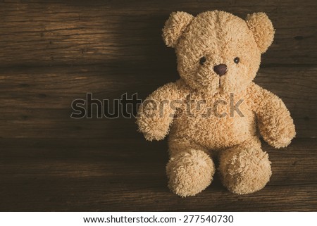 Cute teddy bear sitting on old wood