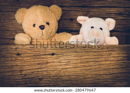 Cute brown teddy bear and Pink Pig in old wood background