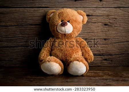 Cute teddy bear sitting on old wood background