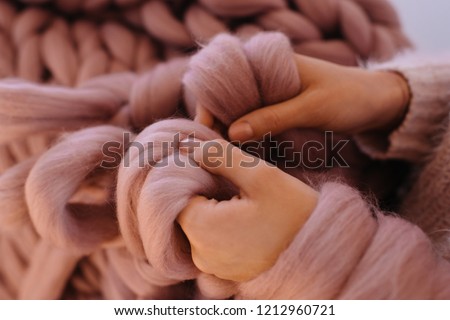 Close up of woman\'s hands knit. Girl knitting with pink wool big merino warm blanket. Rosy tender natural yarn. Cold winter
