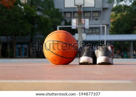 The pair of sport shoes and basketball ball On the cement floor