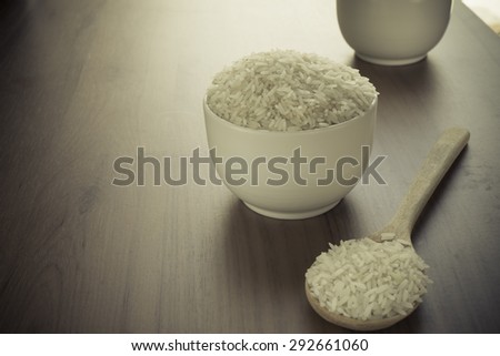 Uncooked rice in a bowl on wooden table.