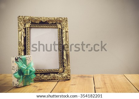 Vintage photo frame with gift box on wooden table over grunge background, Still life style