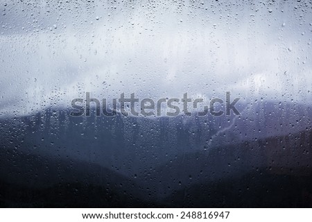 view of the mountains through the glass with raindrops