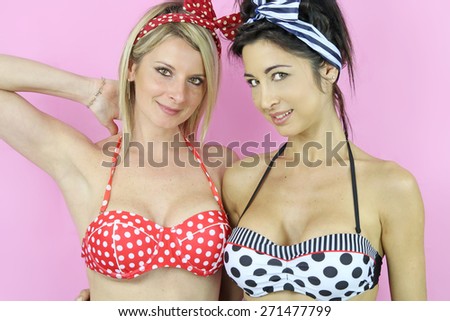 two sexy women dressed in pin up on a pink background