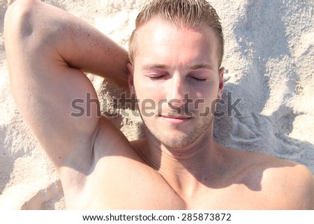 handsome blond man sunbathing at the beach