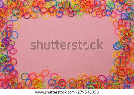 Multicolor loom loop rubber bands frame on the pink  background