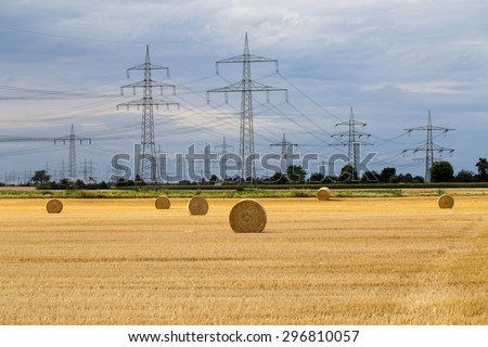 Twisted grain straw  on power lines towers background  before a rain storm,  ancient rural landscape and modern technology on the German field near Eppelheim, Heidelberg and Mannheim